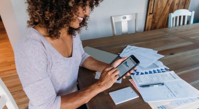 Woman doing finances at home on smart phone